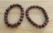 Load image into Gallery viewer, This bracelet is available in 8mm and 10mm. Red Tigers eye is a stimulating stone and can support motivation and a more active sex drive. It's focus on the lower chakras is what gives Red Tiger Eye the power to send higher energies through the organs of the lower half of the body. Red Tiger Eye aids in enhancing confidence and self-esteem as well. It provides motivation to the non-motivated and energizes those who are feeling lethargic.