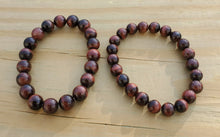 Load image into Gallery viewer, This bracelet is available in 8mm and 10mm. Red Tigers eye is a stimulating stone and can support motivation and a more active sex drive. It&#39;s focus on the lower chakras is what gives Red Tiger Eye the power to send higher energies through the organs of the lower half of the body. Red Tiger Eye aids in enhancing confidence and self-esteem as well. It provides motivation to the non-motivated and energizes those who are feeling lethargic.

